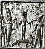 Stèle uit het British Museum. Qetesh, staand op een leeuw en met lotusbloemen en slangen in haar handen. Links Min, met erectie, rechts van haar Resheph.